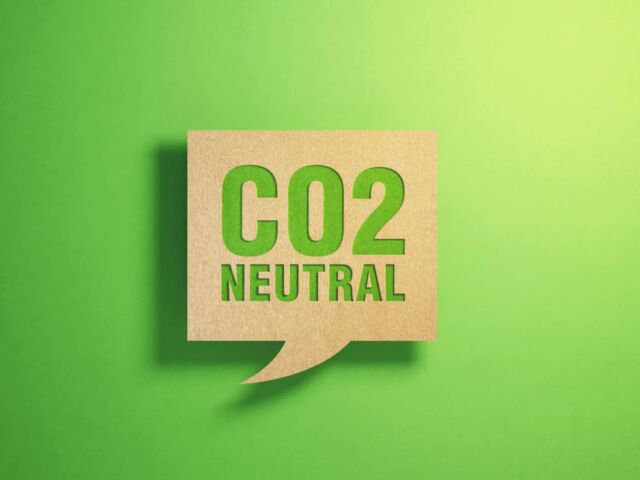 CO2 neutral written chat bubble made of recycled paper on green background. Horizontal composition with copy space. Sustainability concept.